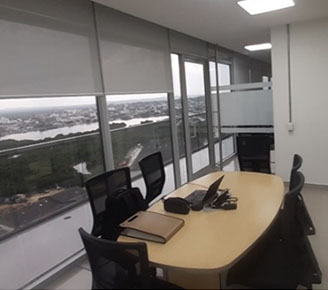 Oficina moderna, con escritorio en madera, black out y sillas negras de malla.